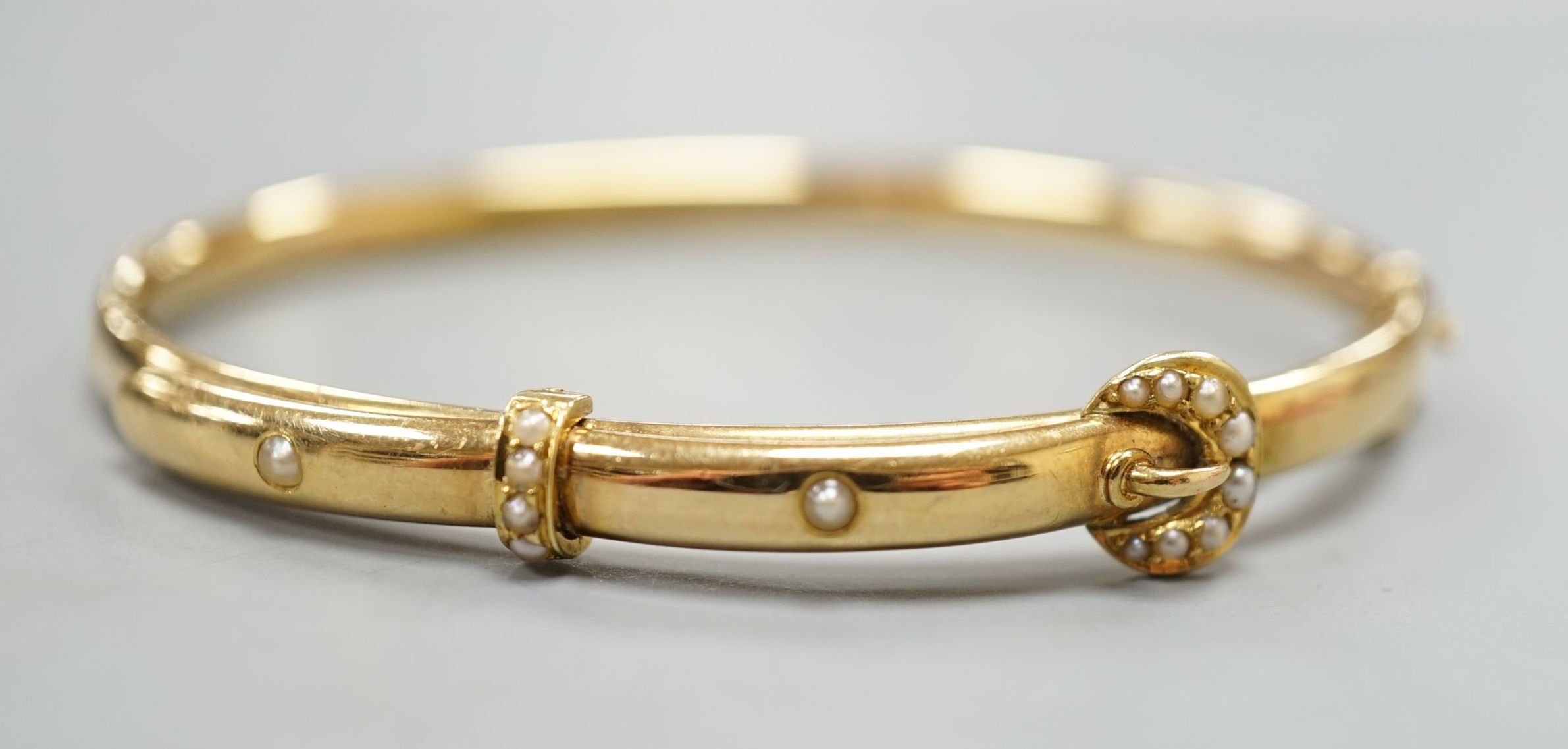 An Edwardian 15ct gold and seed pearl set hinged bracelet, interior diameter 58mm, gross weight 8.3 grams.